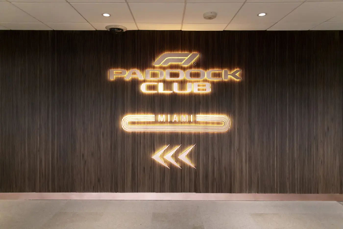Illuminated Paddock Club sign on slatted wood