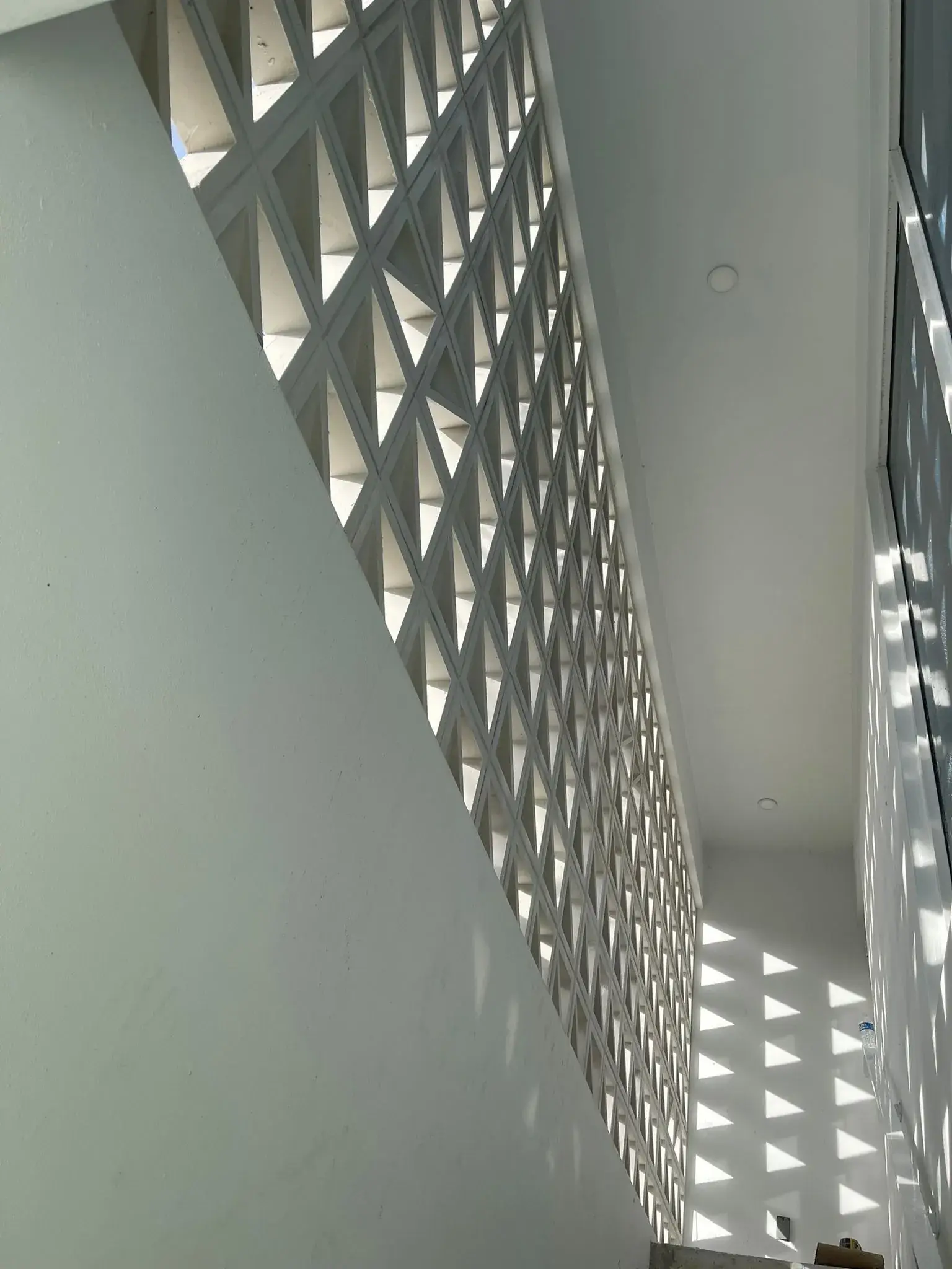 Inside face of the breeze-block screen wall with triangular light pattern across the corridor