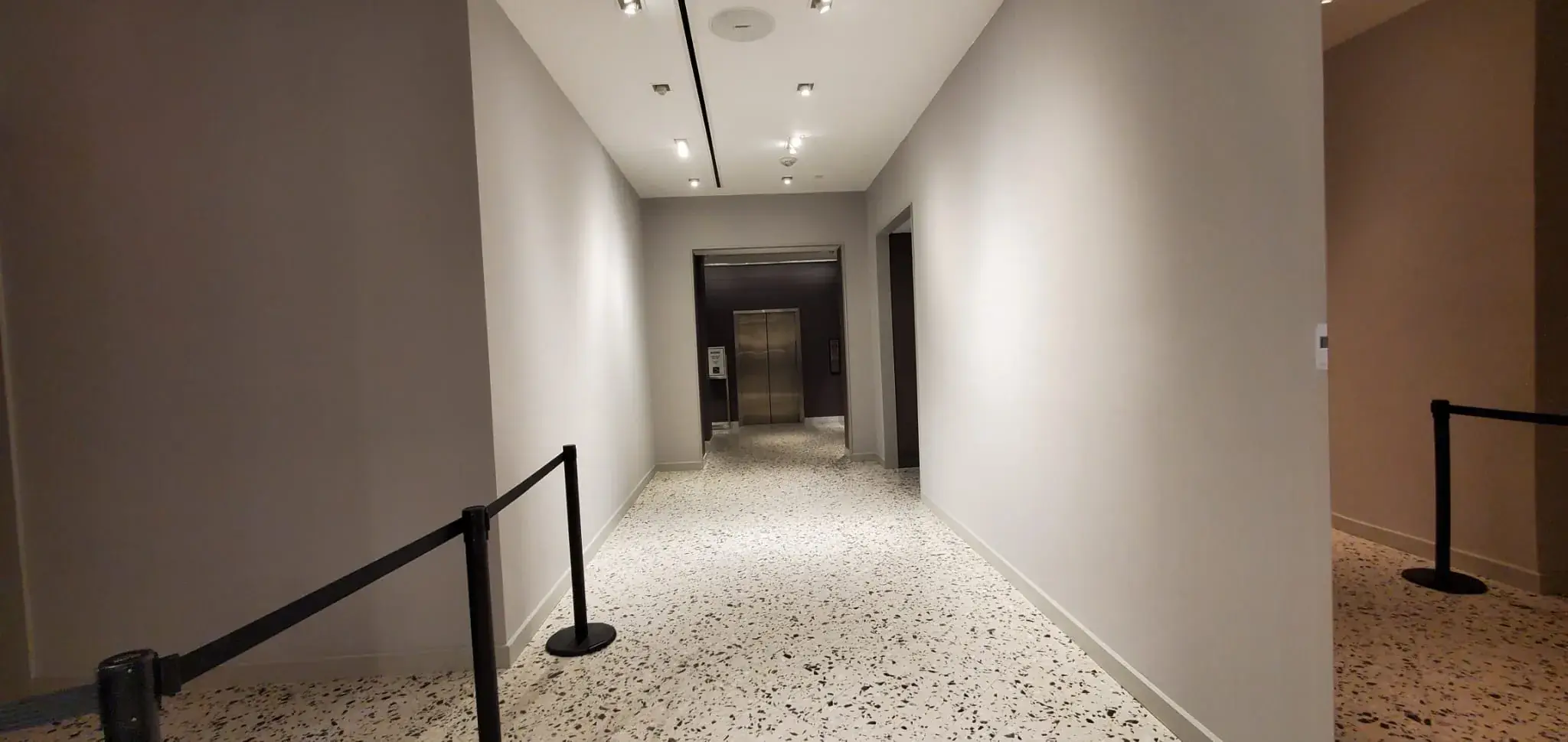 Service corridor toward the elevator with drop ceiling and terrazzo