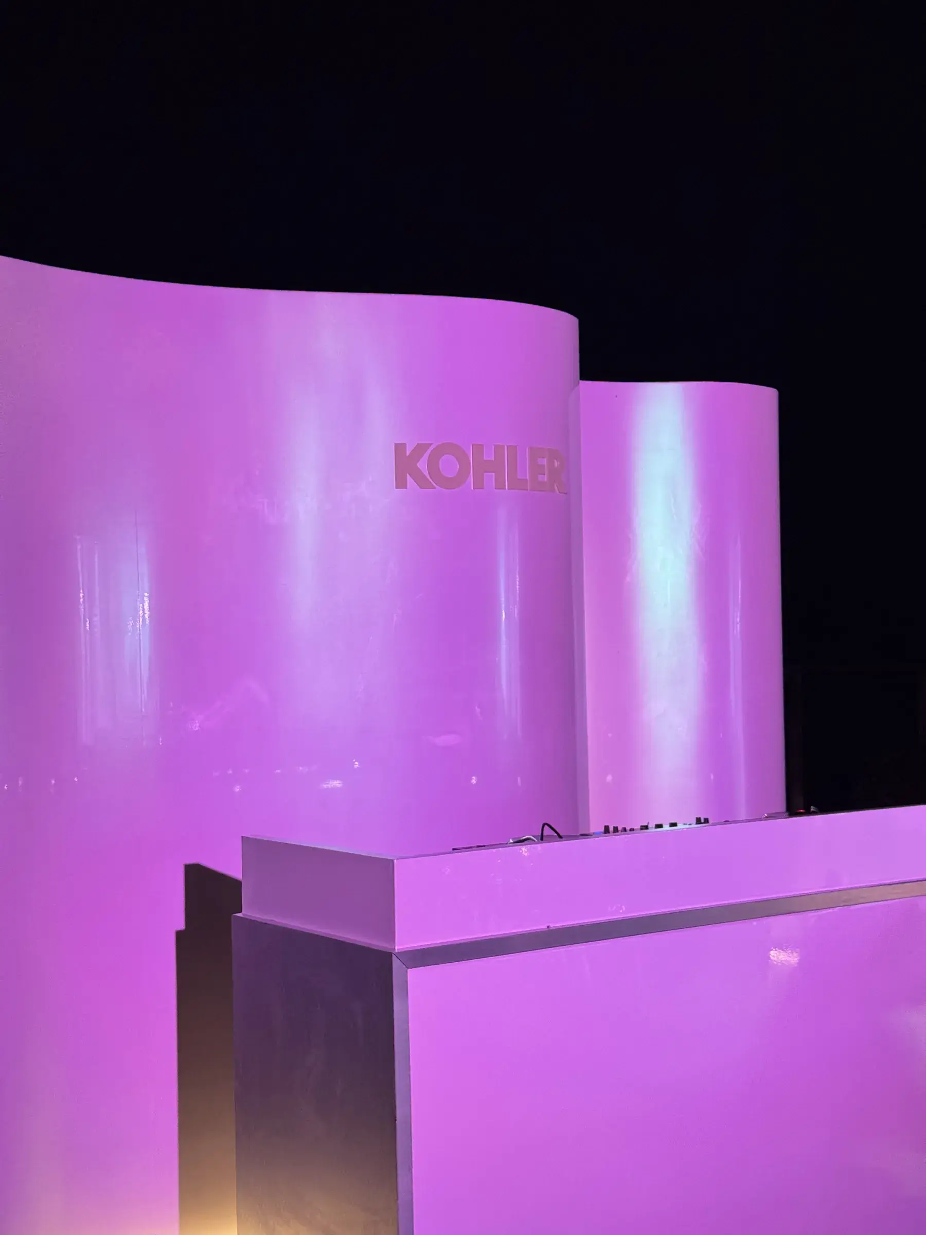 Curved white panels with the KOHLER logo and bar edge in purple light