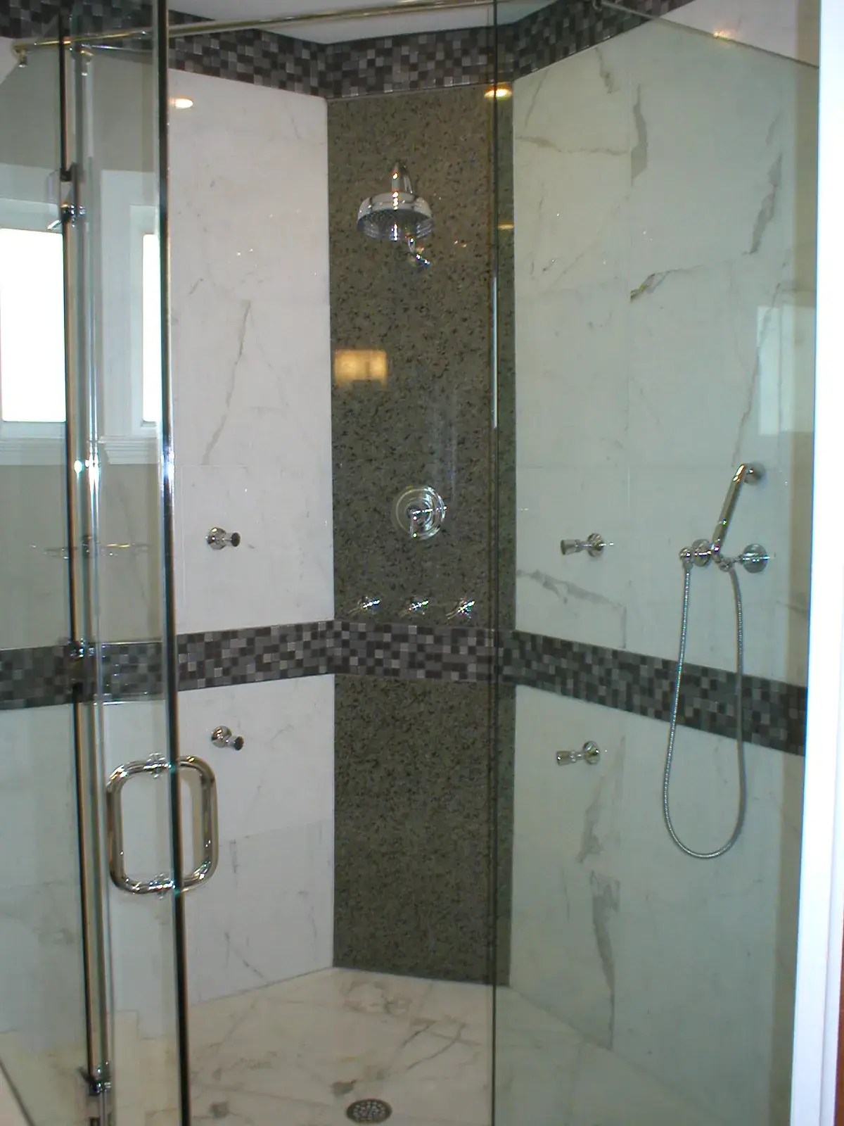 Frameless glass shower, white marble with granite feature panel and mosaic bands, polished fixtures