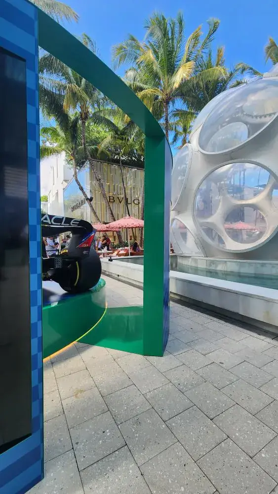 Curved green portal arch framing the dome and Bulgari facade, car tail at lower left