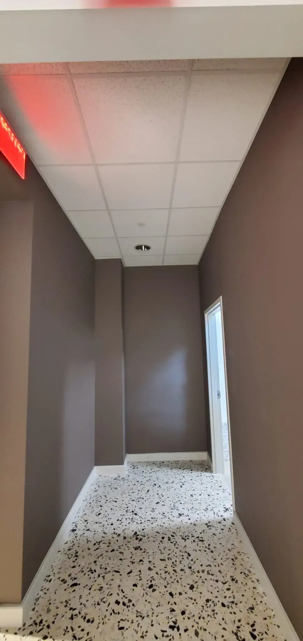 Taupe service corridor with completed drop ceiling and terrazzo