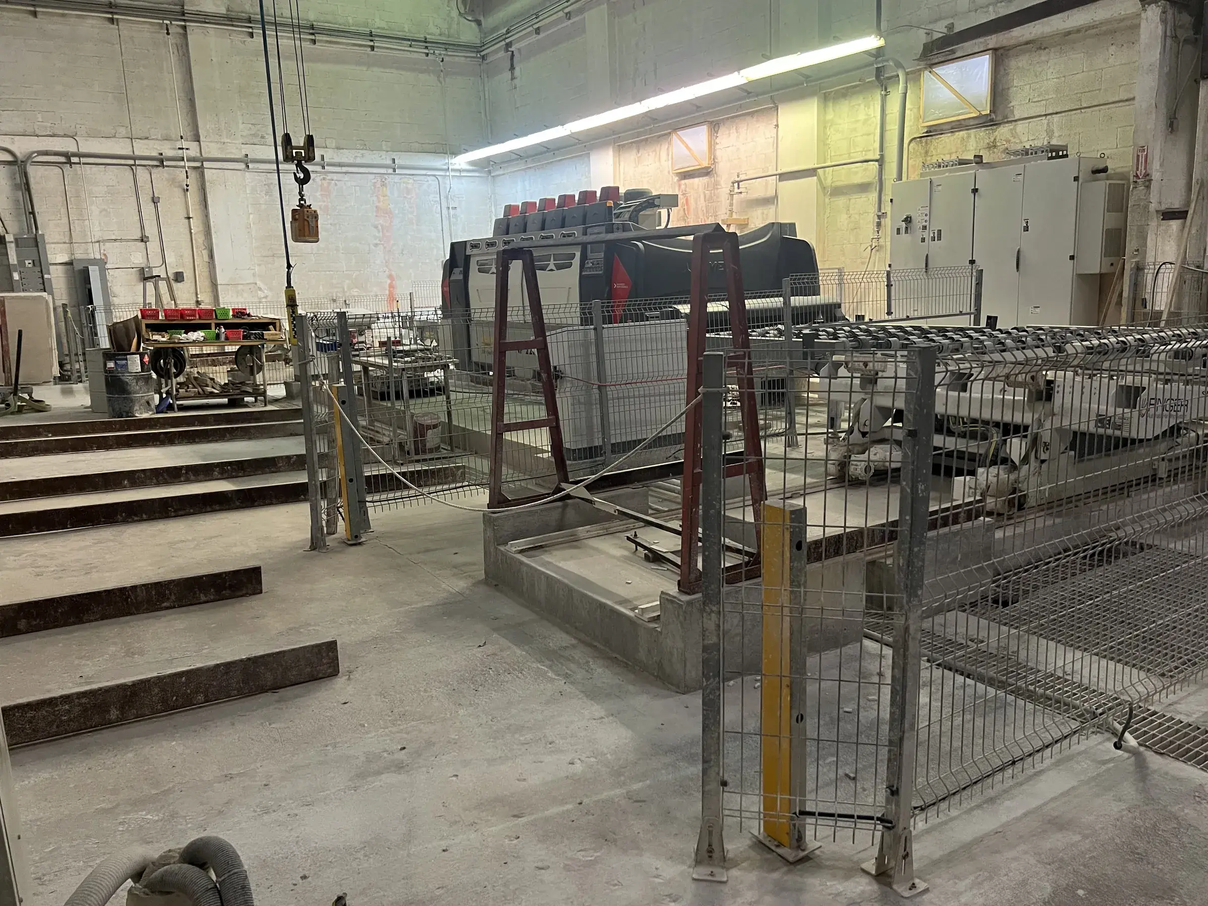 Stepped concrete pads and trench grating in the foreground leading to the fenced polishing line