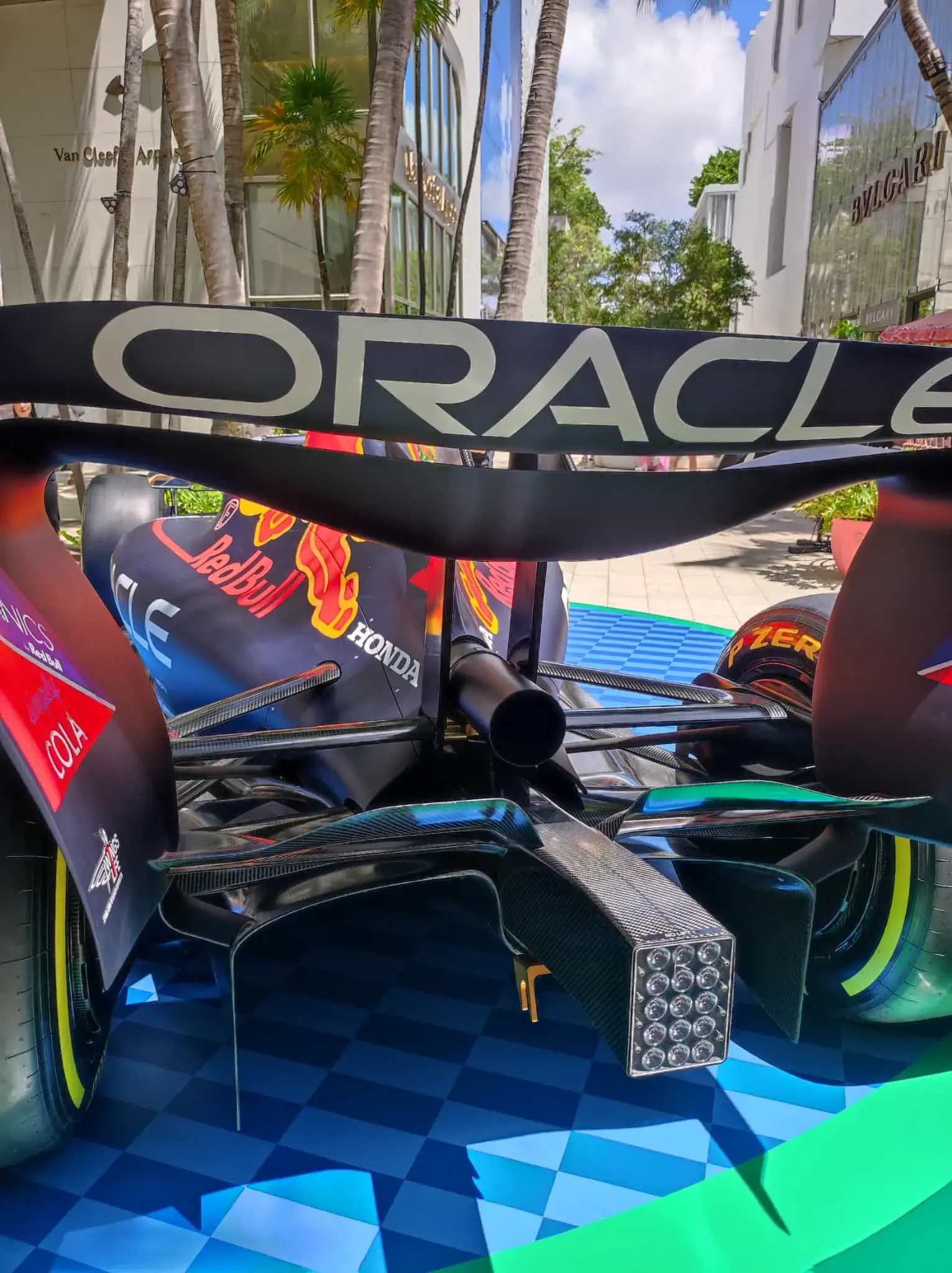 Low rear detail: wing, diffuser and rain light over the checkered deck and glossy green edge