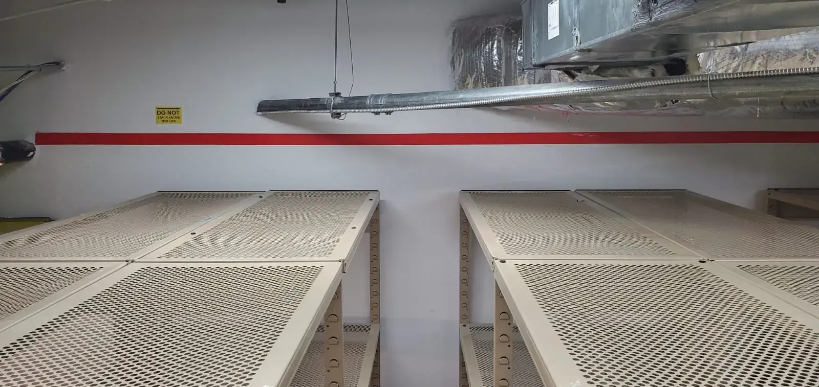 Finished stockroom: rows of perforated steel shelving with red stack-line