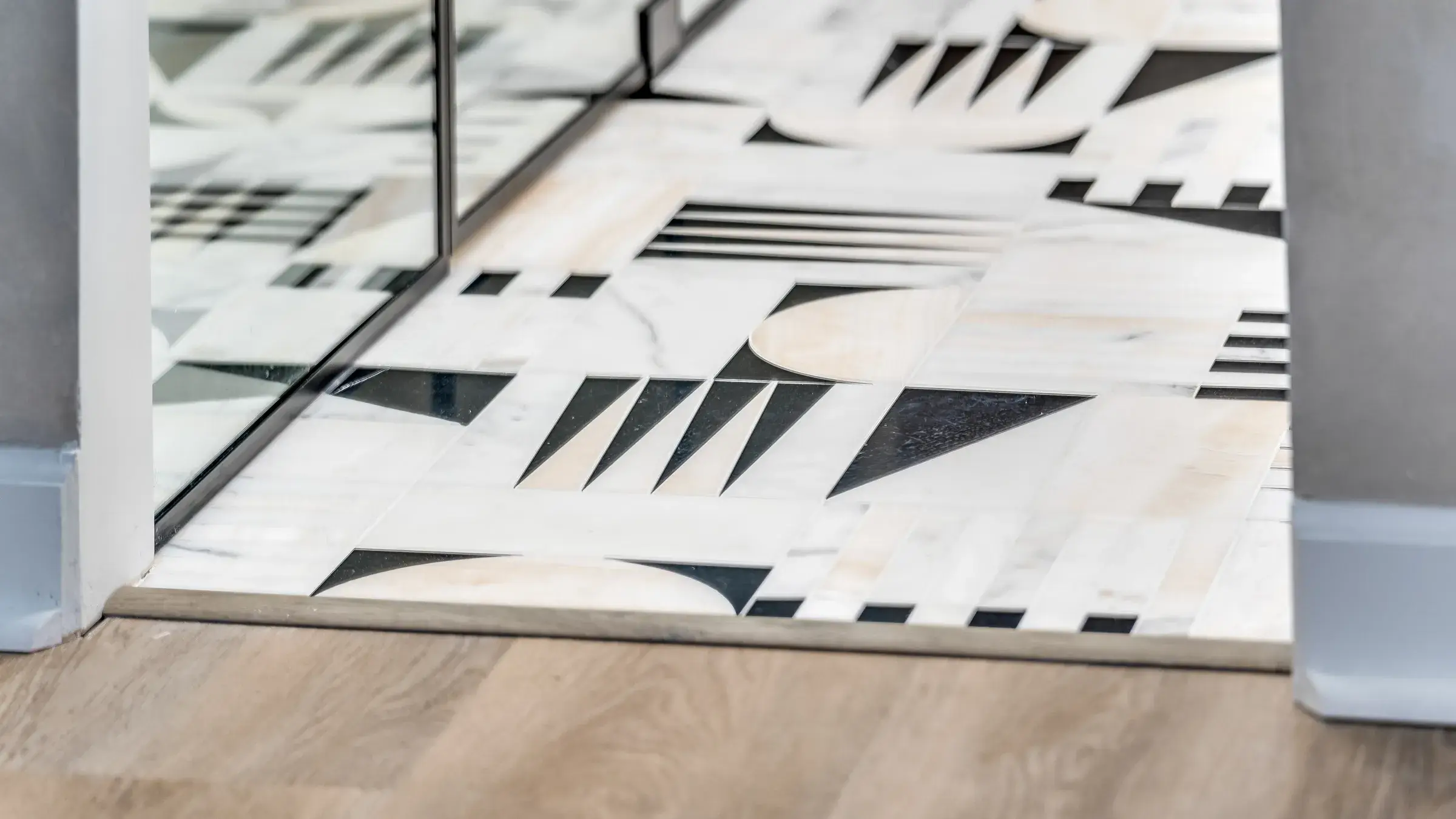 Geometric marble inlay floor at the threshold, meeting the wood floor