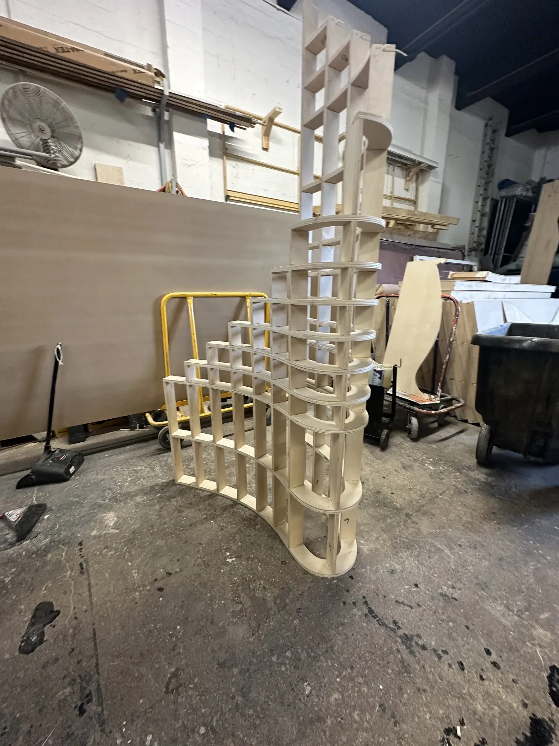 CNC-cut plywood rib skeleton for the curved backdrop panels standing in the shop