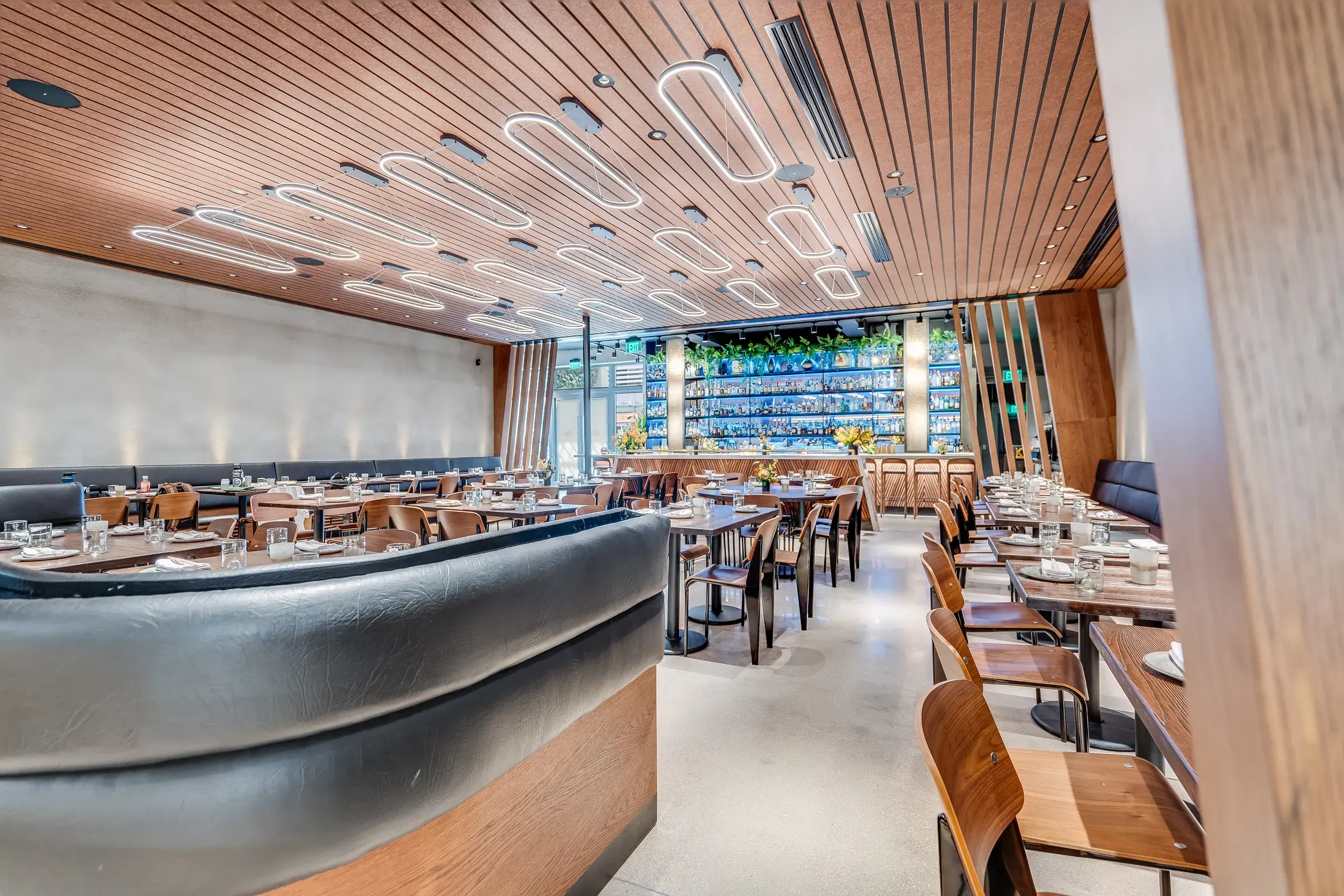 Curved leather booths under the ring-lit slat ceiling