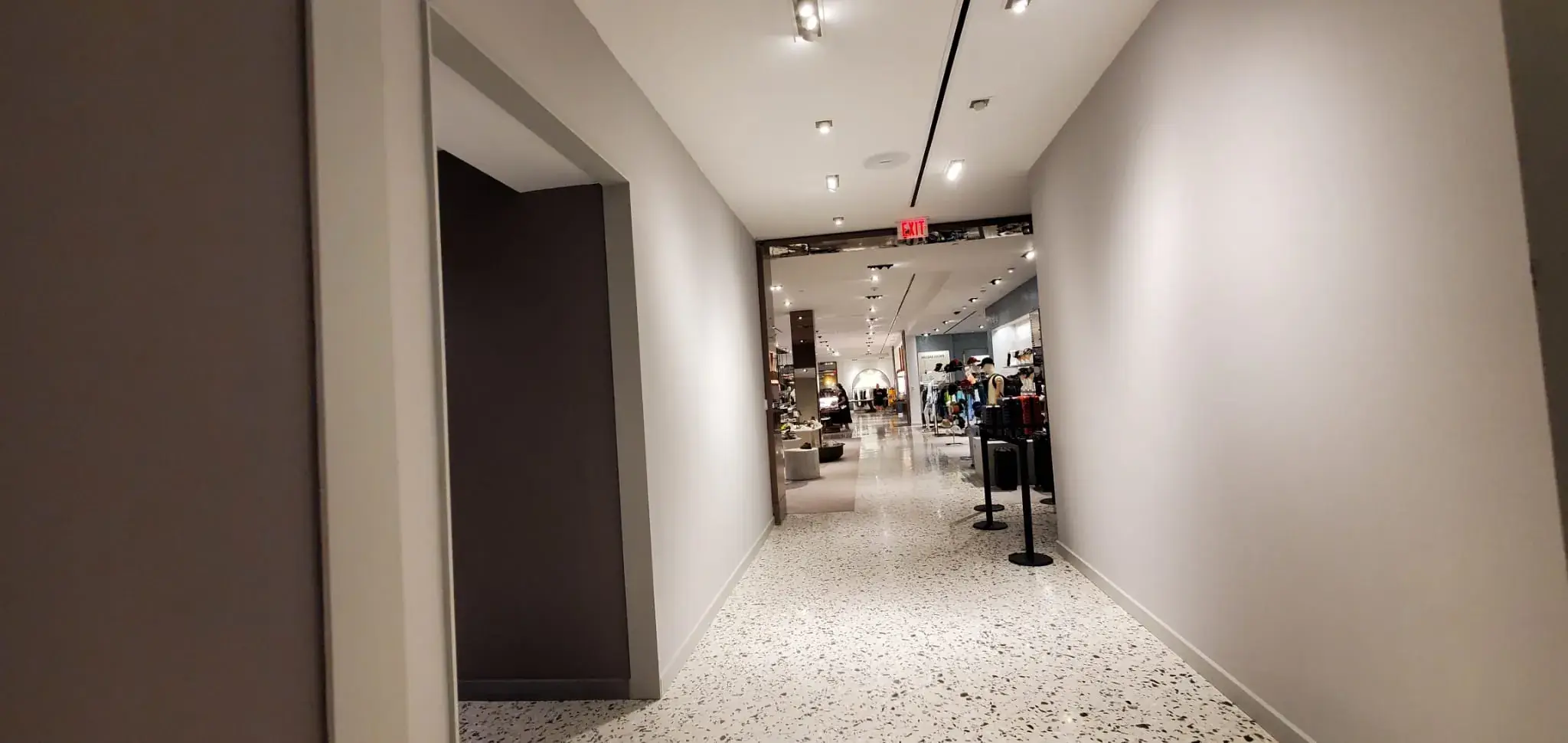 New gray corridor with track lighting and terrazzo opening onto the sales floor