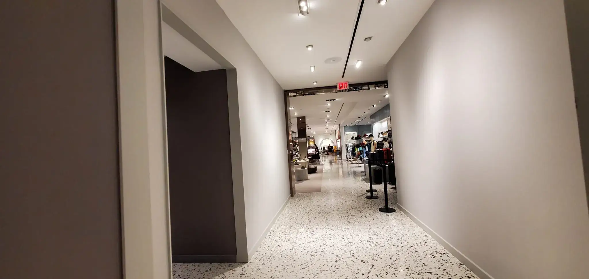 New gray corridor with track lighting and terrazzo opening onto the sales floor
