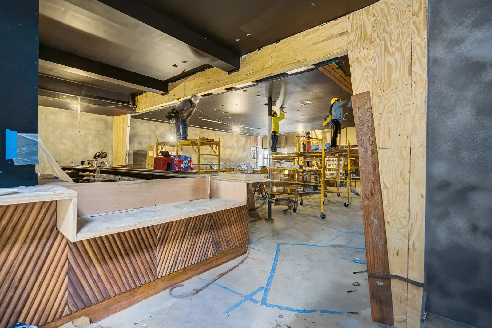 APSOGI crew on scaffolds above a fluted wood bar face during a build-out